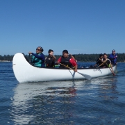 Four people paddling with life jackets in a canoe on the Southern Gulf Islands